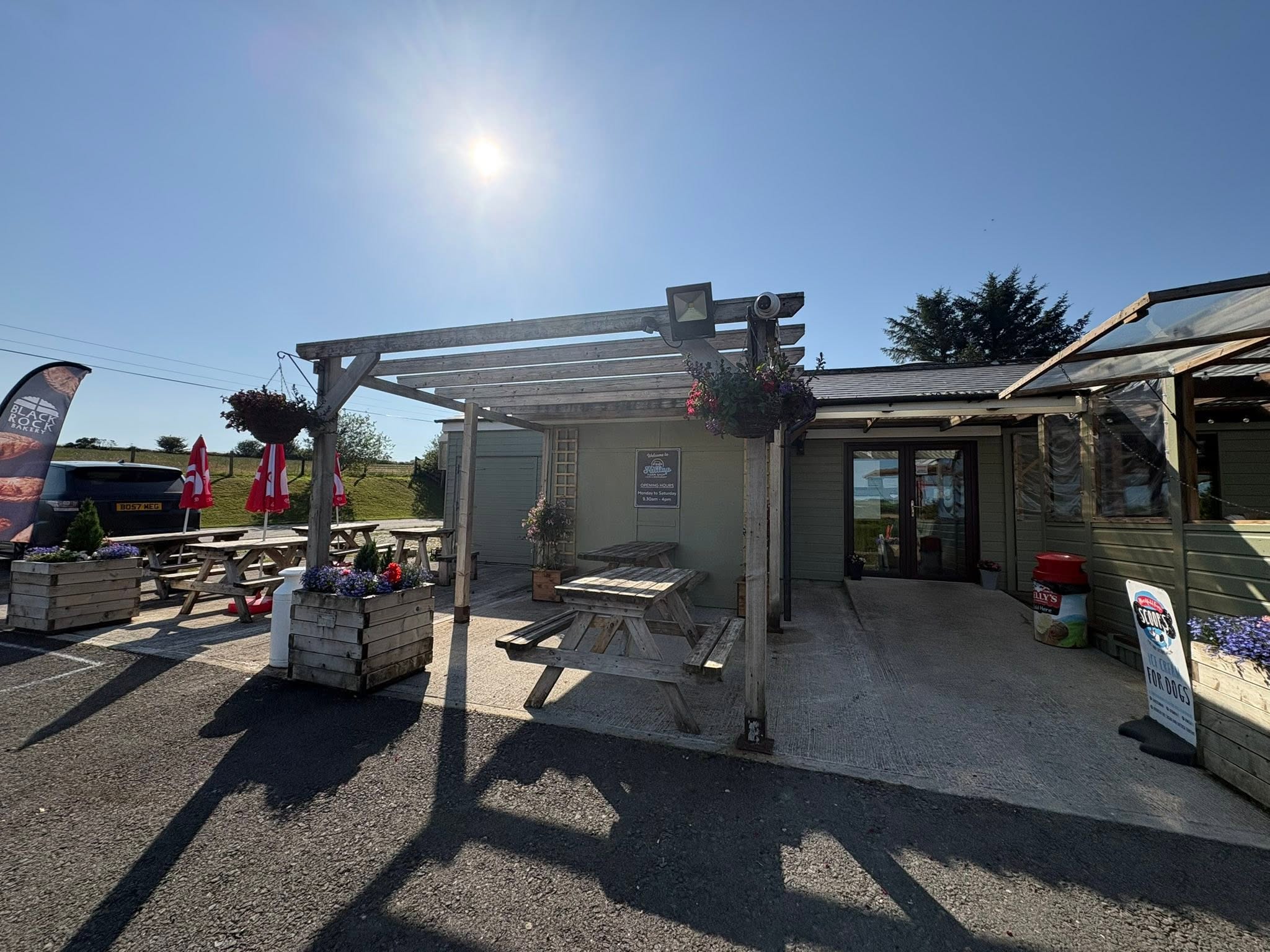 Outdoor picnic tables and flower planters at Hilltop Farm Shop