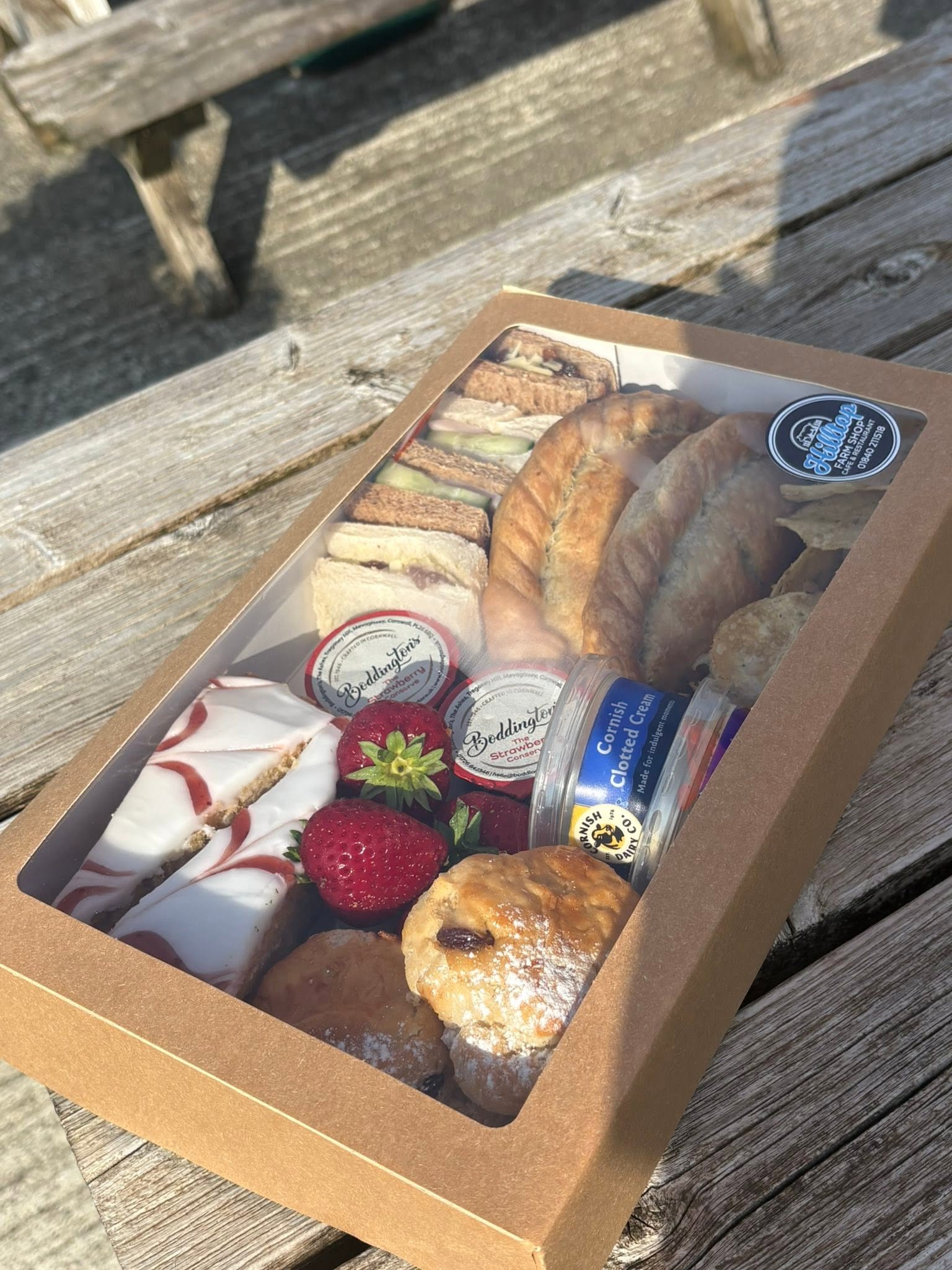 A boxed Hilltop afternoon picnic selection displayed on an outdoor picnic table